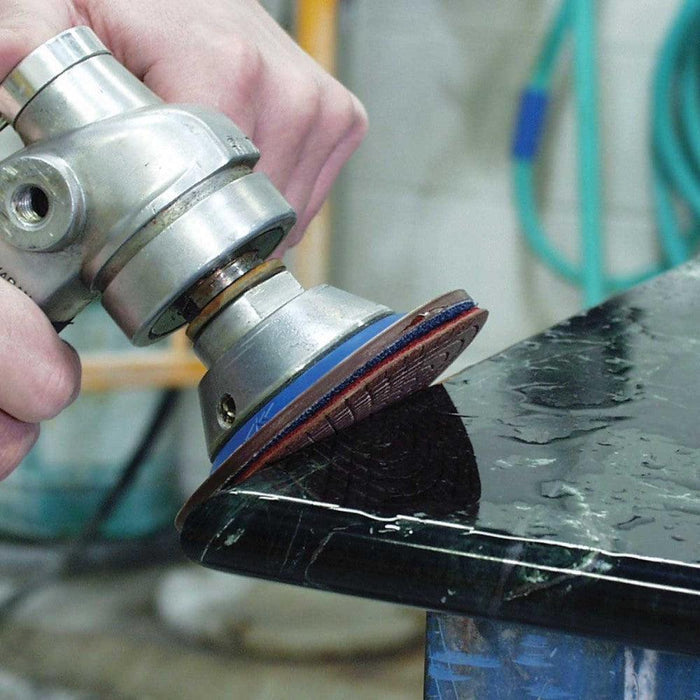 Diamond polishing disc on angle grinder, shows multi-disc pad pattern