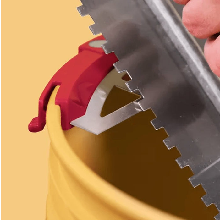 Bucky Scraper close-up: metal blade teeth scraping along a dark bucket edge