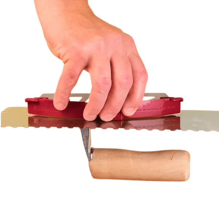 Bucky Scraper scraping a bucket surface; red handle with metal blade extended