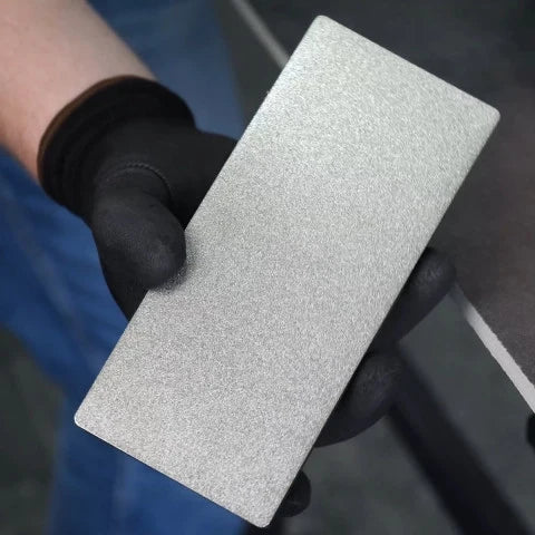 Hand holding a Distar sanding block with a textured surface, wearing a black glove.