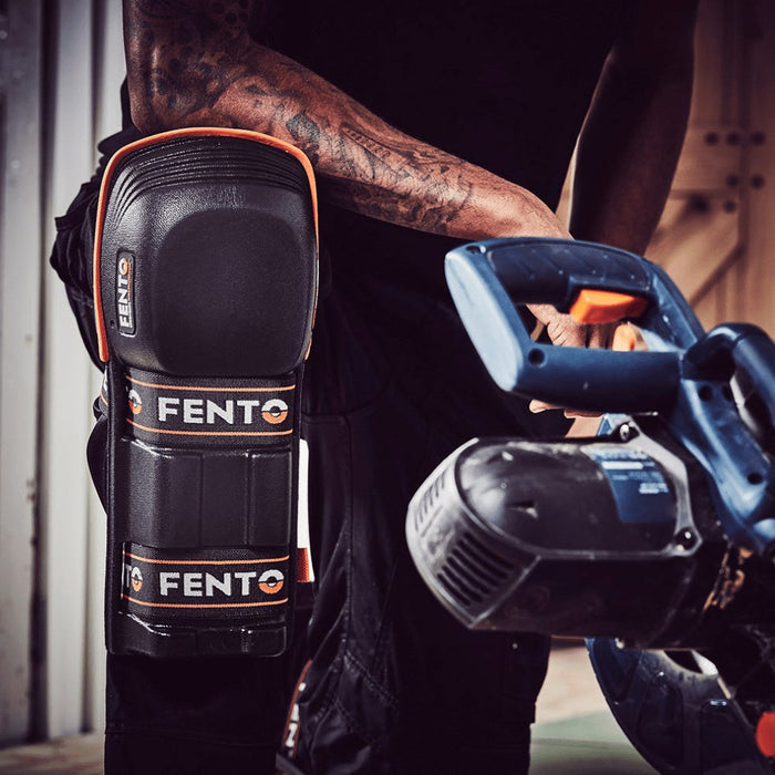 Fento MAX knee pads worn over black pants; hinged black shells with orange edging