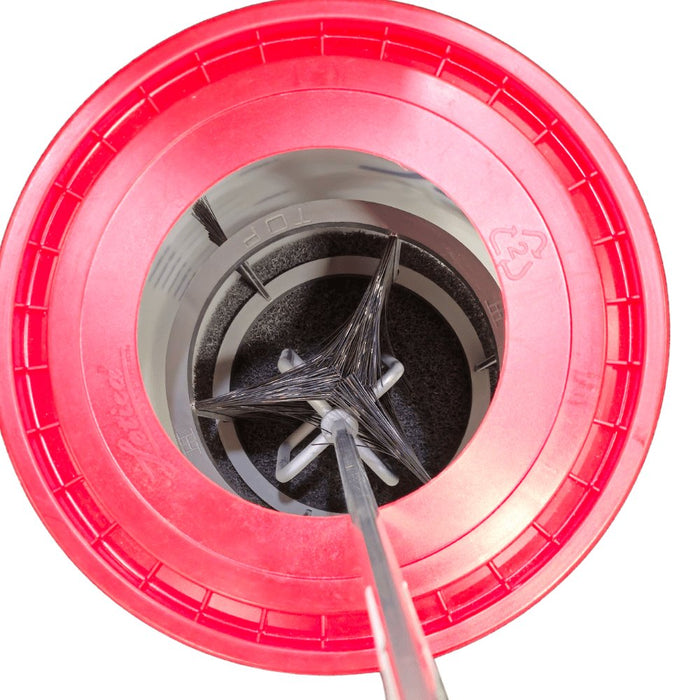 Red mud scrub bucket interior with black scrub pad and gray paddle