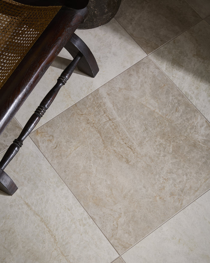 Hoxton Porcelain Amber Matt floor laid diagonally beneath a dark wood and cane plantation chair, with soft daylight falling across the tiles