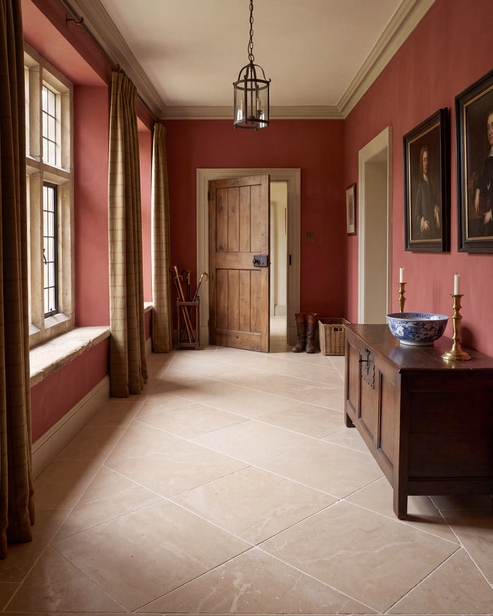 Lacock Limestone Tumbled Finish laid on the diagonal down a deep red hallway, with a stone mullioned window seat, an oak coffer and a hanging lantern