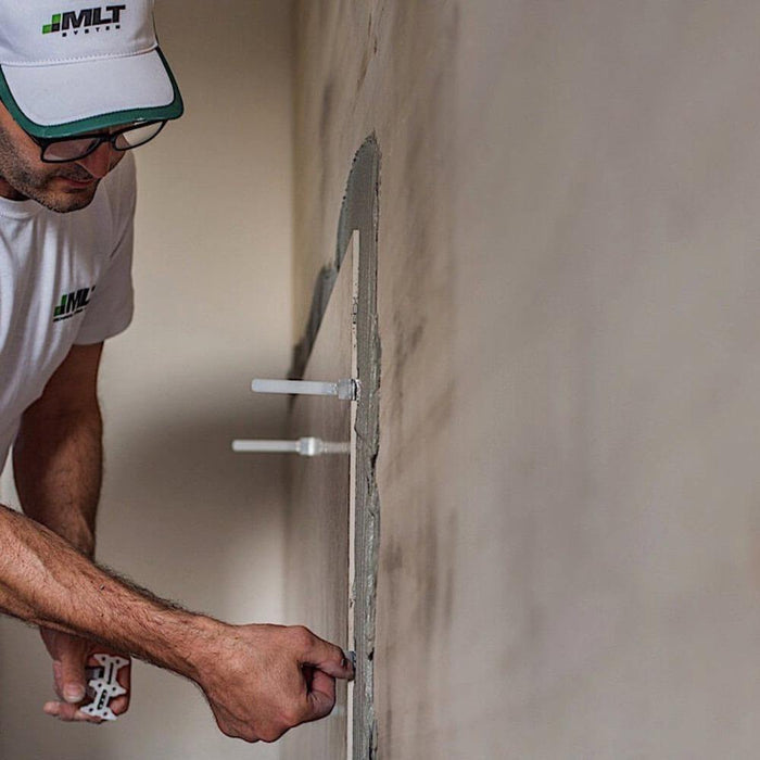 Baseplate installation: hands placing tile leveling baseplates along an edge