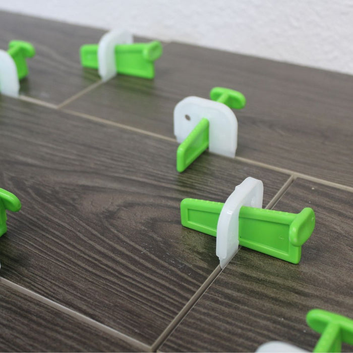 Tile leveling clips installed between tiles, gray brackets with green wedges