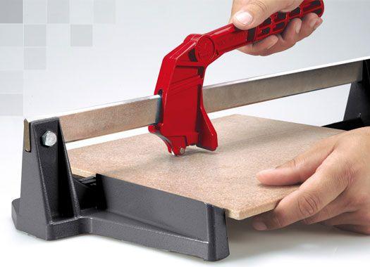 Tile cutter with red handle scoring ceramic tile on gray base