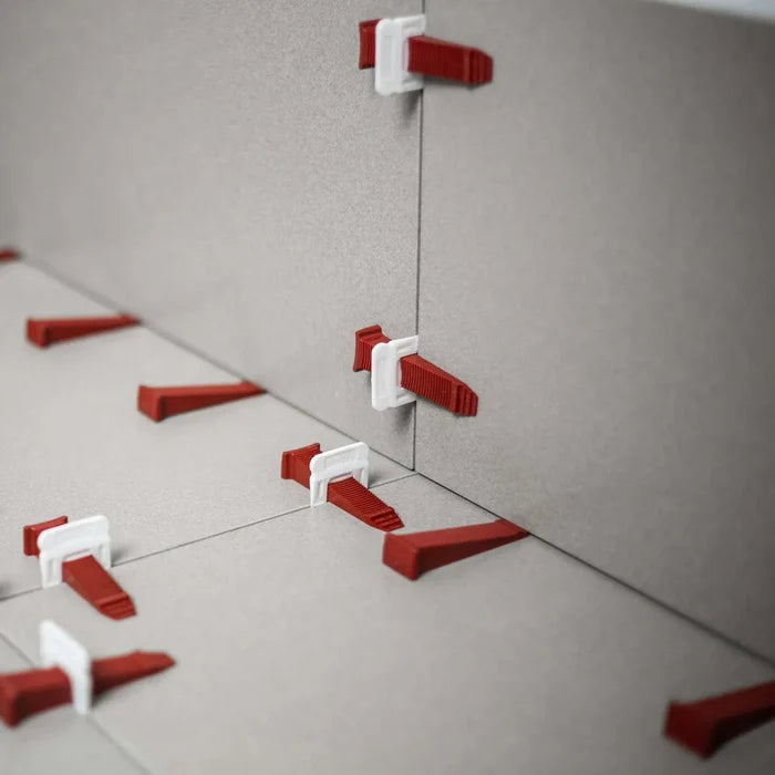 White T-Lock tile leveling clips with red wedges securing floor tiles