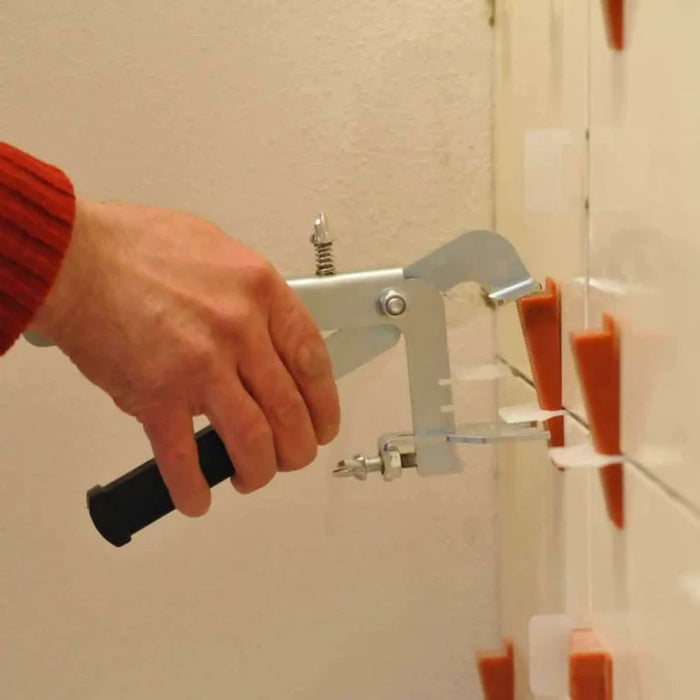 Hand pushing orange tile leveling wedge spacers between tiles