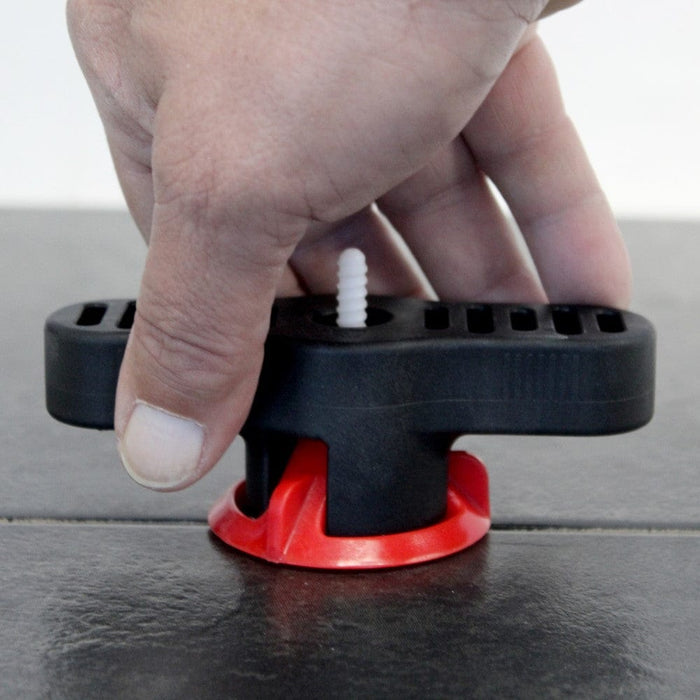 Hand pressing black torque tool on surface; white screw head and red base ring seen