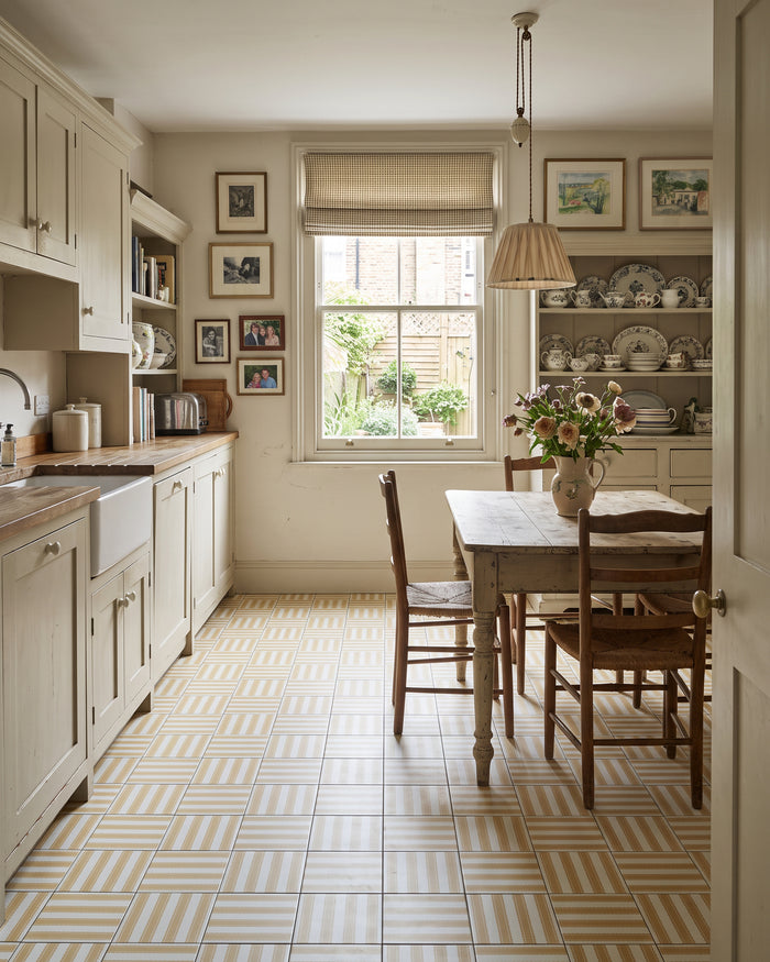 Sanderson Pinetum Stripe Ochre Porcelain across the floor of a cream galley kitchen with a butler sink and a painted dresser