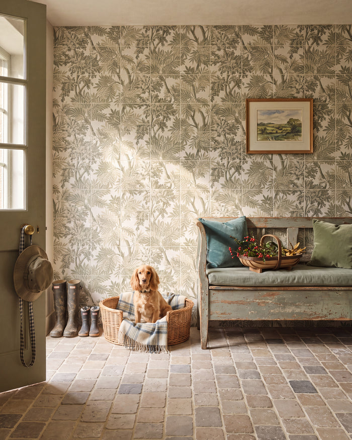 Sanderson Tapestry Trees Forest Mural Porcelain running the full height of a country boot hall, with a spaniel in a wicker basket, wellingtons by a green stable door and a cobbled stone floor