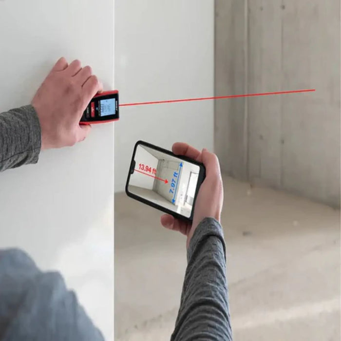 Handheld red laser distance meter showing measured distance on its screen