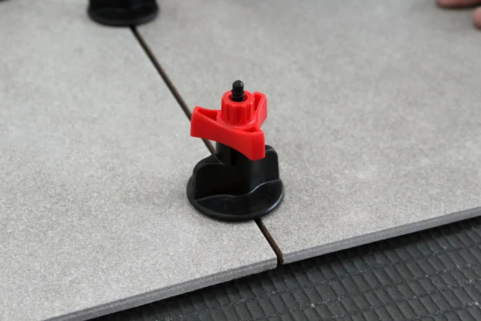 Tile leveling spacer tool between floor tiles, black suction base with red head